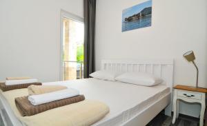 a white bedroom with a bed and a chair at Apartments Edera in Tivat