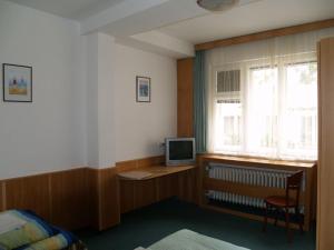 a bedroom with a desk with a computer and a window at Pension Pod Šibeňákem in Strmilov