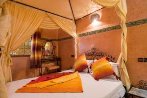 una camera da letto con letto a baldacchino e cuscini arancioni e gialli di Riad Saad a Marrakech