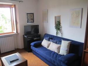 a living room with a blue couch and a tv at Casa Valeria in Cinigiano