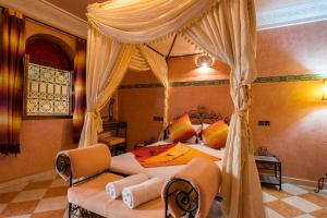 una camera con letto a baldacchino e 2 sedie di Riad Saad a Marrakech