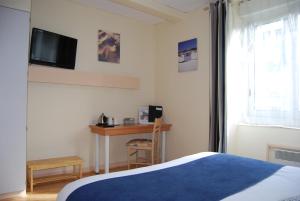 1 dormitorio con 1 cama, escritorio y TV en Le Bretagne - Hôtel Spa & Sauna, en Douarnenez