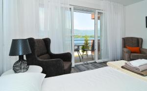 a bedroom with a bed and two chairs and a balcony at Apartments Edera in Tivat
