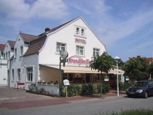 a white building with a hotel on the street at Hotel Strandpavillon in Baabe