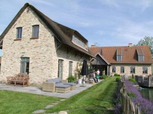 a large stone house with a thatched roof at BB-hof ter boone in Kapelhoek