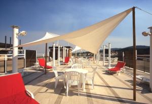 una terraza con sillas, mesas y un dosel blanco en G. Hotel Capitol en Chianciano Terme