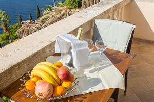 una mesa con una bandeja de fruta y copas de vino en Apartments Villa Victoria en Dubrovnik