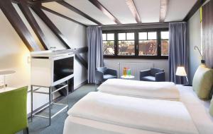 a room with two beds and a tv in it at Hotel Le Colombier in Obernai