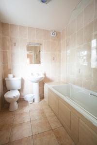 a bathroom with a toilet and a tub and a sink at Barons Court Hotel in Wolverhampton