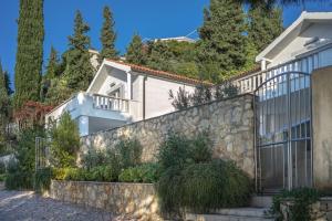 a house with a stone retaining wall and a fence at Apartments Fortunata in Primošten