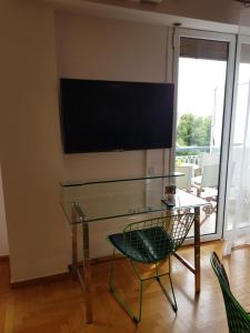 a glass table with a chair and a television on a wall at Park at Home Apartment in Athens