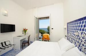 a bedroom with a bed and a desk and a window at Hotel Aurora in Amalfi