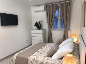 um quarto com uma cama, uma televisão e uma janela em Alyon em Nice