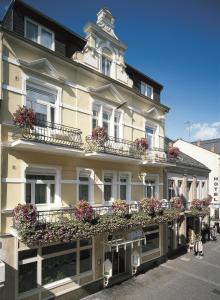 Un grand bâtiment blanc avec des fleurs sur les balcons dans l'établissement Hotel Krupp, à Bad Neuenahr-Ahrweiler