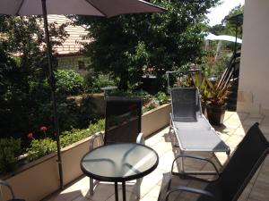 drie stoelen en een parasol op een patio bij LUX Apartman in Balatonfüred