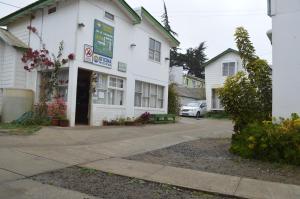 un edificio blanco con un cartel en el costado en Cabañas Hecmar, en Pichilemu