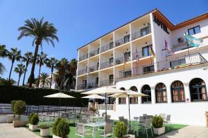 un hôtel avec des tables, des parasols et des palmiers dans l'établissement Arcos de Montemar, à Torremolinos
