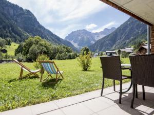 a patio with chairs and a table with a view of mountains at Gartenappartement Kirchdorf by A-Appartments in Brand +18 photos