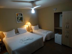 a hotel room with two beds with white sheets at Hotel Mirante in Barra Velha