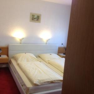 Bett in einem Zimmer mit zwei Leuchten in der Unterkunft Hotel-Restaurant Hellmann in Schwarzenbruck