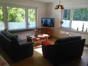 ein Wohnzimmer mit 2 Stühlen, einem Tisch und Fenstern in der Unterkunft Mia und Michel im Sauerland in Bad Berleburg
