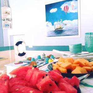 una mesa cubierta con platos de fruta y un tazón de sandía en Perfume Do Mar, en Porto San Giorgio