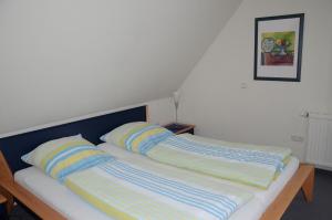 ein Bett mit zwei gestreiften Kissen darüber in der Unterkunft Inselresidenz Seeschwalbe Langeoog in Langeoog