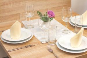 una mesa de madera con platos y gafas blancos y una flor rosa en Appartments Gartenblick, en Illmitz