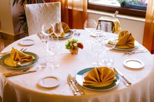a table with a white table cloth with plates and wine glasses at Hotel Riva Del Sole in Cefalù