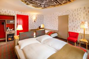 une chambre d'hôtel avec un lit et un fauteuil rouge dans l'établissement Swiss Night by Fassbind, à Zurich