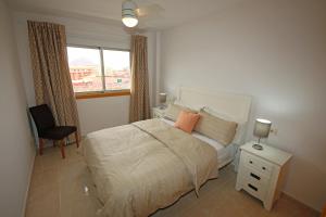 a bedroom with a bed and a window and a chair at LA PERLA by RENTMEDANO superb luxury duplex, private roof terrace, ocean view, pool, WiFi and parking in El Médano +21 photos