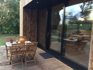 un porche cubierto con mesa y sillas en Abarolodge, en Hannut