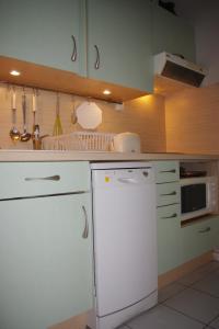 eine Küche mit einem weißen Kühlschrank und einer Mikrowelle in der Unterkunft Maison à ROYAN PONTAILLAC in Royan