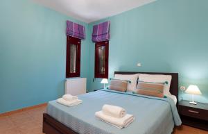 a blue bedroom with a bed with towels on it at Evalexia Villa in Kalamaki +19 photos