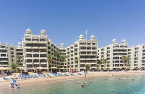a group of hotels on a beach with people in the water at Sunrise Holidays Resort -Adults Only in Hurghada