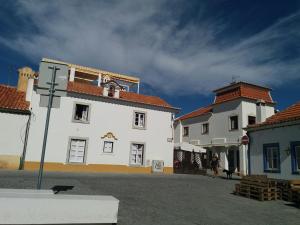 a large white building with a person standing next to it at Apartamento Rosa in Vila Nova de Milfontes