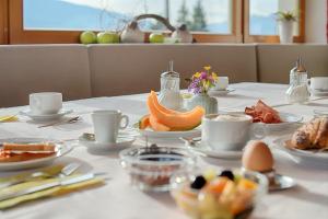 une table avec des assiettes de nourriture et des tasses dessus dans l'établissement Garni Schorneck, à Brunico