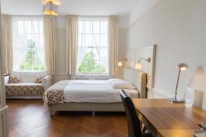 a bedroom with a bed and a table and windows at Landgoed Huize Glory in Bergen aan Zee
