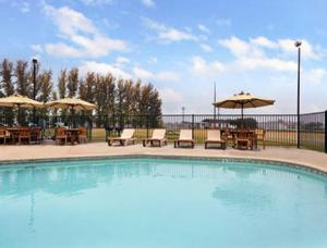 una piscina con mesas, sillas y sombrillas en Travelodge by Wyndham Lemoore Near Naval Air Station, en Lemoore