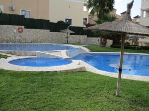 a swimming pool with an umbrella in the grass at Jardin de Alba in Villacosta