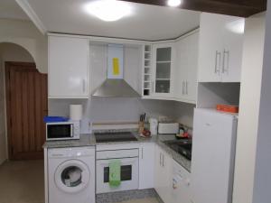 a kitchen with white cabinets and a washer at Jardin de Alba in Villacosta