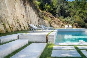 a swimming pool with lounge chairs next to a mountain at Semeli in Kokkari