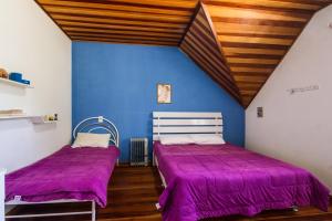 two beds in a room with purple sheets at Casa do Esquilo Campos do Jordão Area Externa de 2000 m2 in Campos do Jordão
