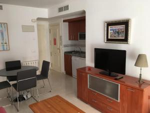 a living room with a tv and a table with chairs at Apartamento en Calpe, playa de La Fossa, primera línea, AA in Calpe