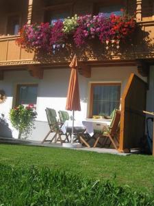 a patio with chairs and an umbrella and flowers at Apartment Galtenberg in Alpbach