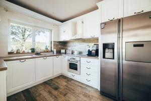 Una cocina con gabinetes blancos y un refrigerador de acero inoxidable. en Casa De La Munte, en Mănăstirea Humorului