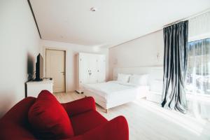 Dormitorio blanco con cama y sofá rojo en Casa De La Munte, en Mănăstirea Humorului