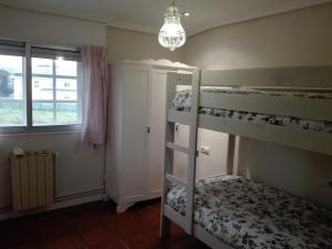a bedroom with three bunk beds and a chandelier at Casacovas in Ferrol