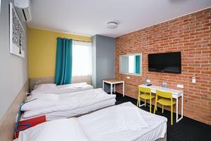 a room with four beds and a brick wall at Tamada in Ozorków