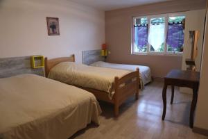 a room with two beds and a table and a window at Hotel Restaurant De La Roche in Les Sauvages